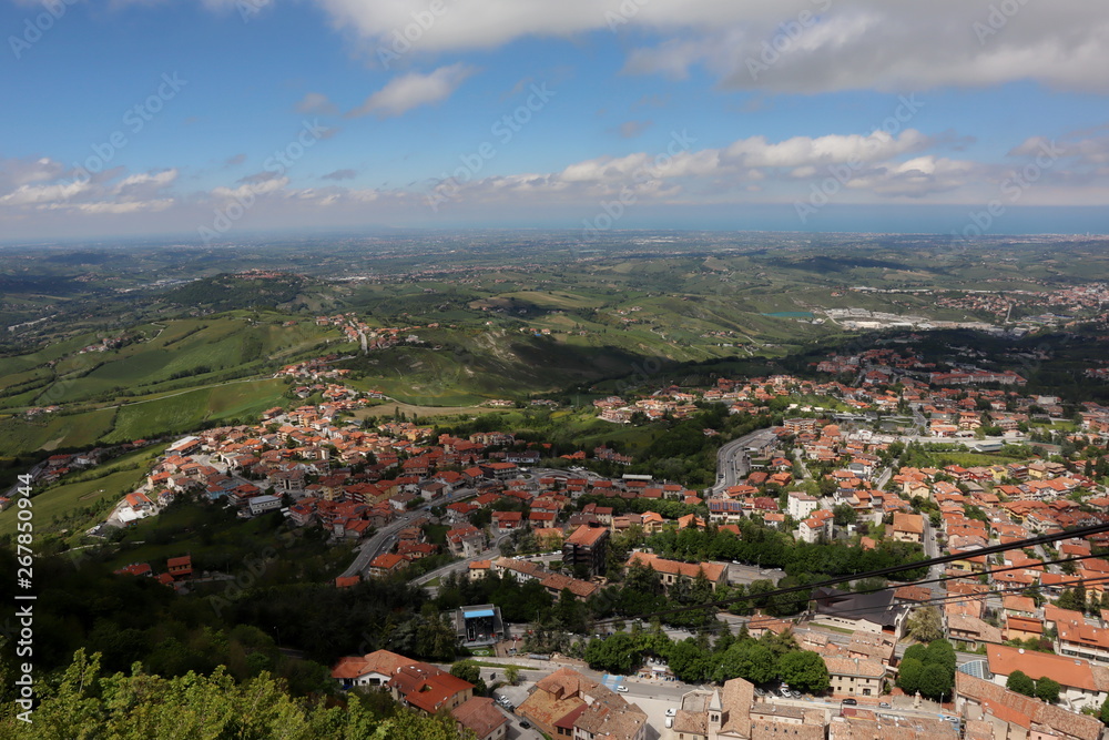 panoramic view from top of Fortress Guaita on Mount Titano on city San Marino ,Italy with beautiful blue sky with clouds on sunny day. View towards the sea and over the San Marino villages 