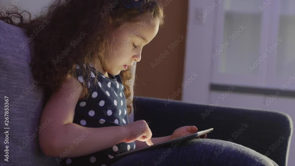 Cute Child Entertaining With Tablet. Little Girl Spending Leisure Time Playing Mobile Game in the and Crushes the Bright Screen With Her Hand. Concept of:Happy Childfood, Technology, Childen Play Cute Child Entertaining With Tablet. Little Girl Spending Leisure Time Playing Mobile Game in the and Crushes the Bright Screen With Her Hand. Concept of:Happy Childfood, Technology, Childen Play