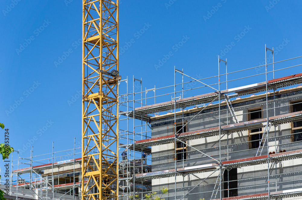 building under construction - construction site with crane and scaffolding at the facade