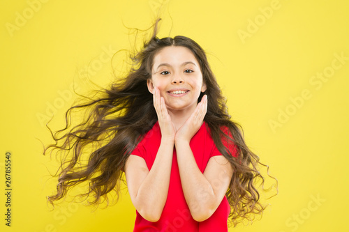 Girl adorable kid long wavy hair yellow background. Wind can also damage hair. Strong persistent winds can create tangles and snags in wavy and curly long hair. Things you doing to damage your hair