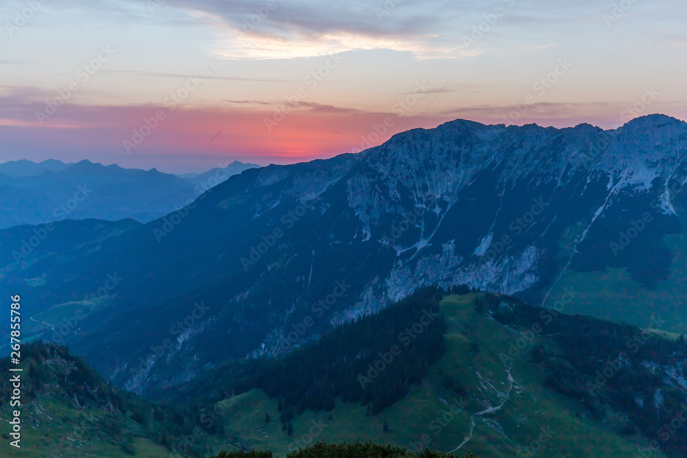 Plakat Berglandschaft während des Sonnenuntergand mit Gipfeln und Wolken sowie blauen Himmel