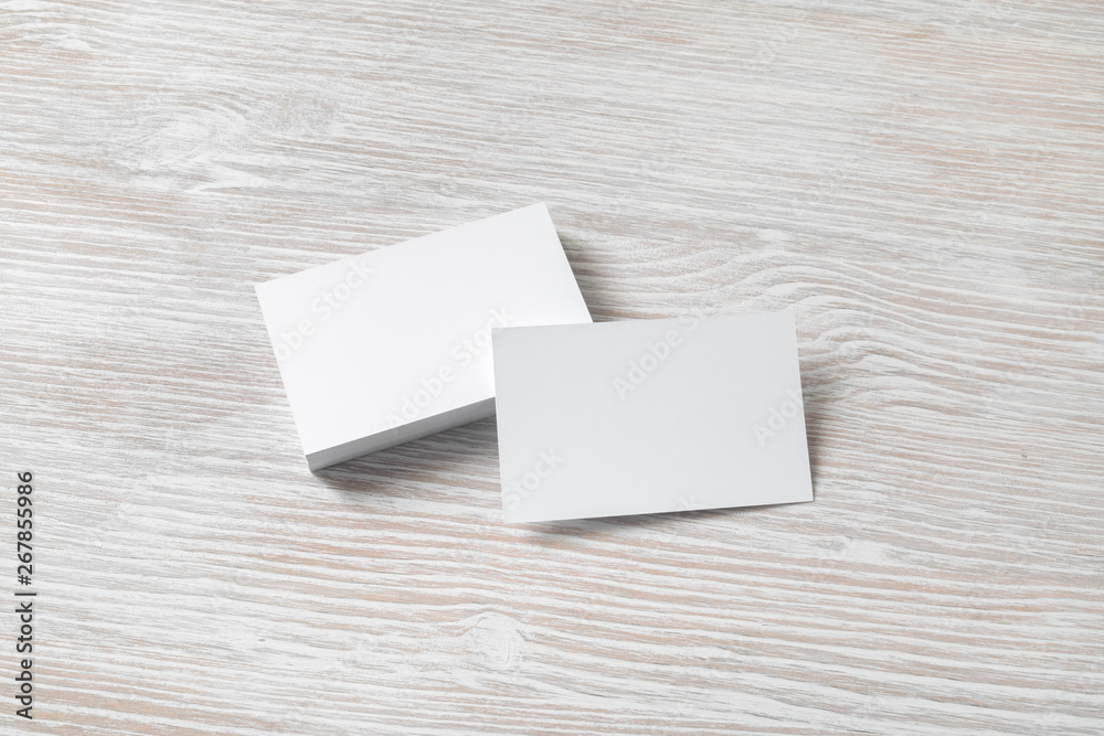 Photo of blank white business cards with soft shadows on light wooden background. For design presentations and portfolios. Photo of blank white business cards with soft shadows on light wooden background. For design presentations and portfolios.