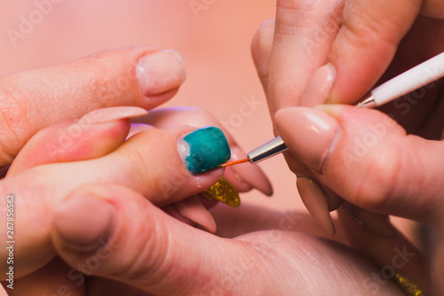 A woman paints nails with a turquoise gel polish. Salon procedures at home. close-up