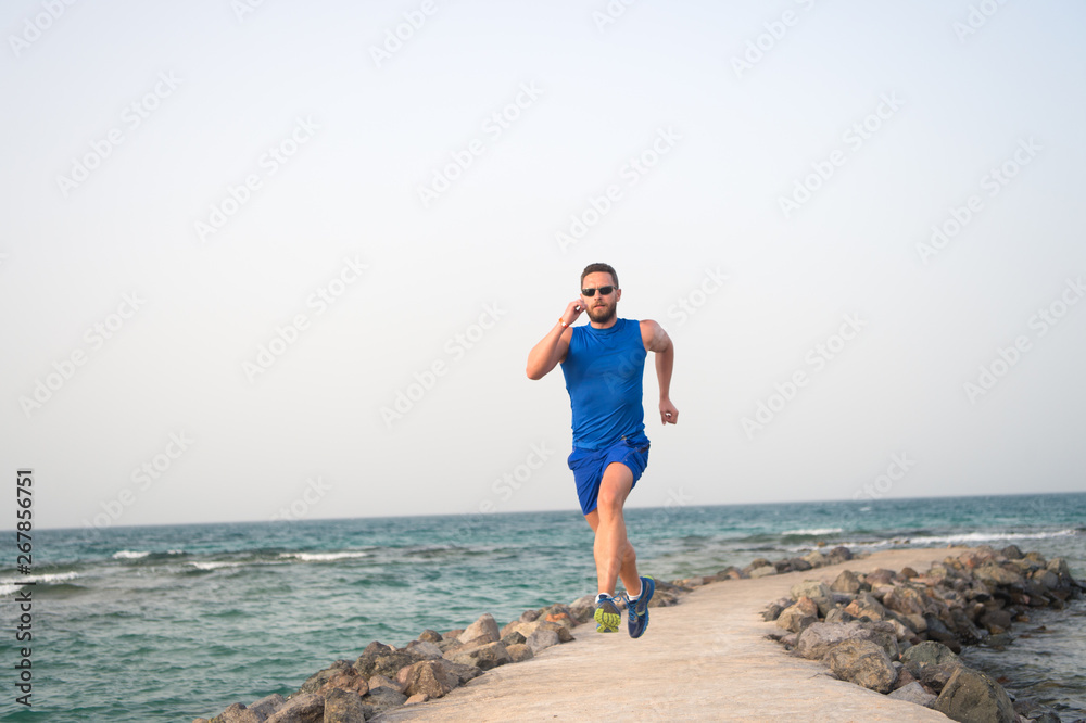 Run fast or be last. Running man on beach. Runner training outdoors. Fit male sport fitness exercising in summer. Running sport and hobby. Daily workout great result. Man professional fitness coach
