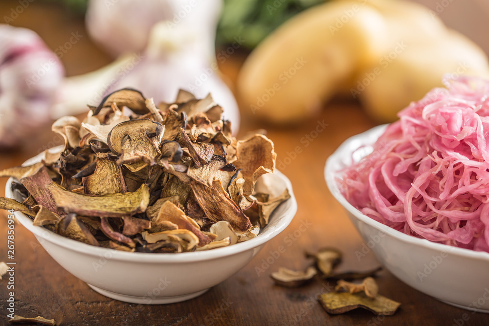 Sour cabbage and dried mushrooms in bowl on wooden table