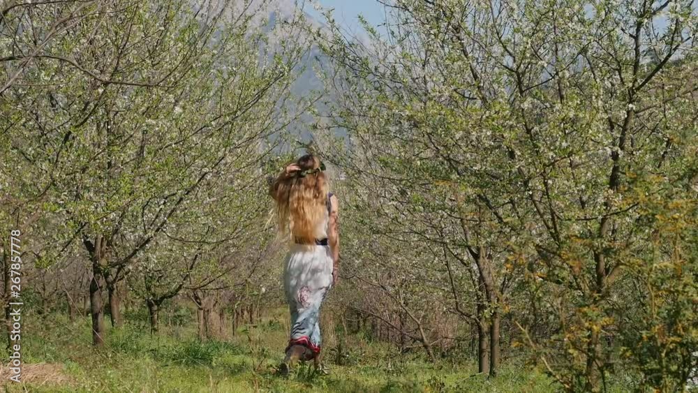 Young beautiful woman in long dress jumping in spring blossom garden Young beautiful woman in long dress jumping in spring blossom garden