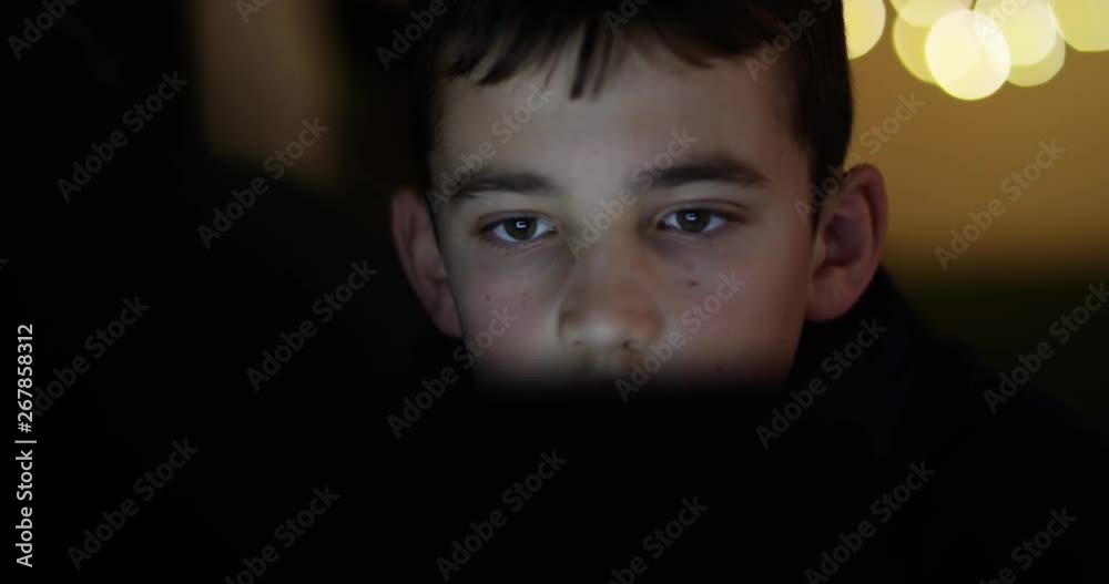 4k, Young boy engrossed in playing games on a touchscreen tablet. Slow motion. 4k, Young boy engrossed in playing games on a touchscreen tablet. Slow motion.