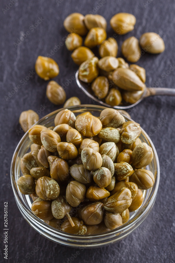 pickled capers on a dark stone background