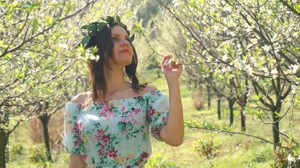 Young beautiful woman smells blossom trees.