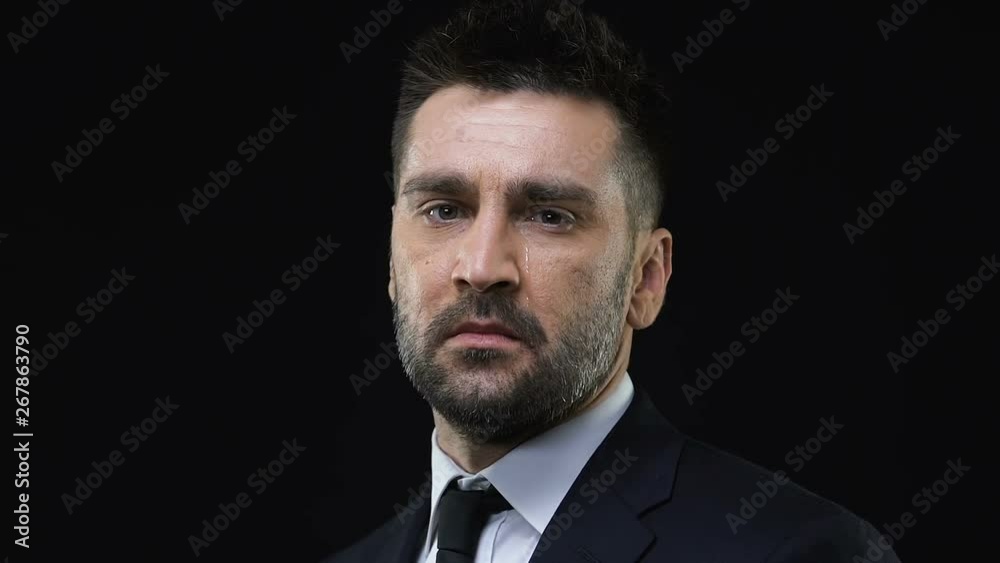 Crying business man looking at camera isolated on black background, problems Crying business man looking at camera isolated on black background, problems