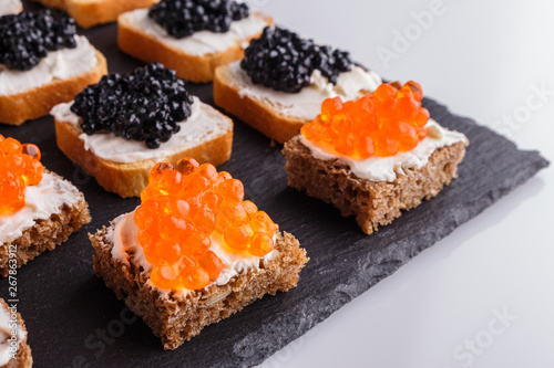 Snack with red and black caviar on a stone plate