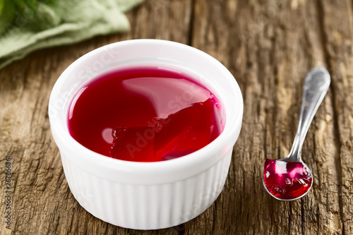 Rote Götterspeise oder Wackelpudding in weißer Schüssel mit Löffel an der Seite (Selektiver Fokus, Fokus in die Mitte des Bildes) photo