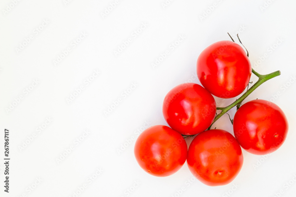 Organic red tomatoes with a green twig handful, lie on a white background. There is a place for text. Organic red tomatoes with a green twig handful, lie on a white background. There is a place for text.
