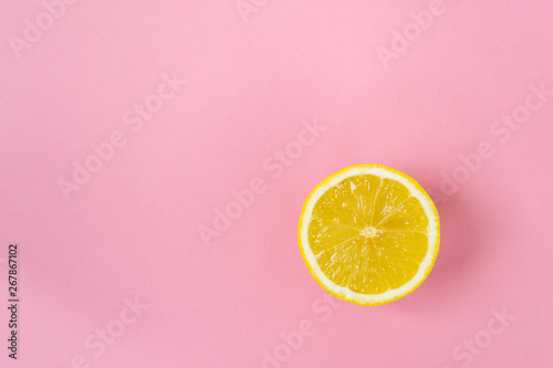 Round slice of yellow lemon, on a pink background.
