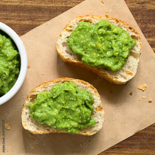 Fresh avocado cream or guacamole on baguette slices, photographed overhead with natural light (Selective Focus, Focus on the top of the avocado cream)