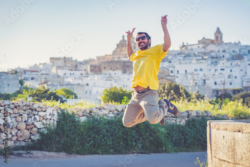 happy tourist jumping with ostuni city in background, apulia region, Italy