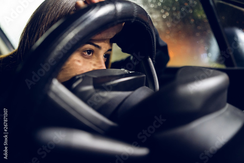 Young woman holding a car driving wheel in a rainy night rain bored in a traffic jam © Miljan Živković