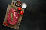 raw beef steak with herbs and spices on a stone background with copy space for your text