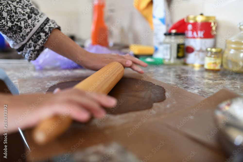 Mom rolls the dough. chocolate dough. Hands work with cake dough recipe preparation. Women's hands, Women's hands roll out the dough. Mom rolls dough on a kitchen board with a rolling pin