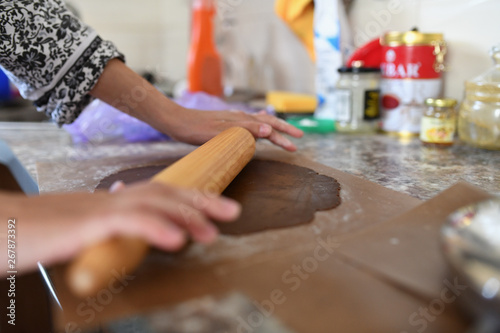 Mom rolls the dough. chocolate dough. Hands work with cake dough recipe preparation. Women's hands, Women's hands roll out the dough. Mom rolls dough on a kitchen board with a rolling pin