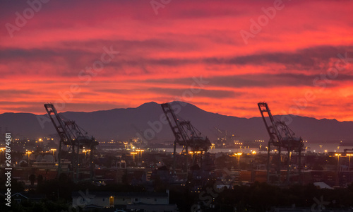 Sunrise over the Port of Los Angeles in San Pedro, California, Novermber 2018, with red orange color of smoke from Woolsey fire with large giant cranes and San Bernardino mountains in background. photo