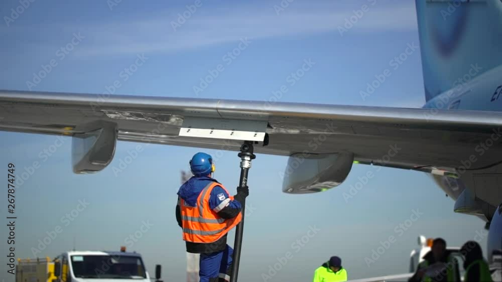 Airport airplane crew refueling aircraft on airline by technical staff maintenance ground. Preparing airplane for departure. repair of aircraft service worker use fuel hose on aircraft wing, on stairs