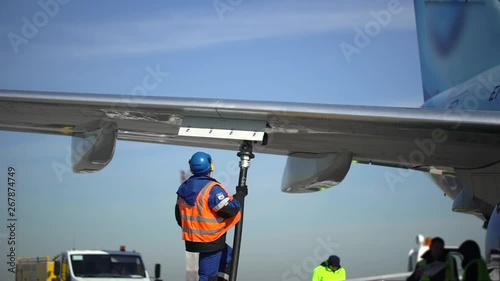 Airport airplane crew refueling aircraft on airline by technical staff maintenance ground. Preparing airplane for departure. repair of aircraft service worker use fuel hose on aircraft wing, on stairs
