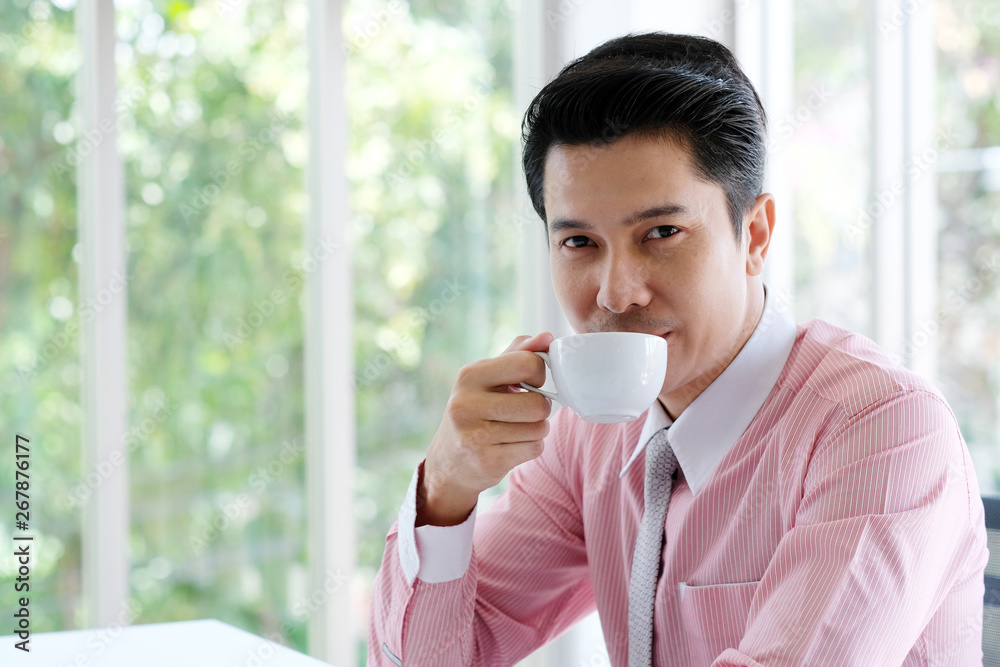 Young asian businessman drinking coffee at office, office life and business concept Young asian businessman drinking coffee at office, office life and business concept