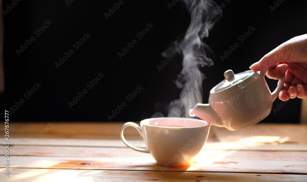 hot tea cup on wood table, Hot drink . with steam,warm soft light, dark  background.Good morning Tea or Have a happy day message concept. Stock  Photo