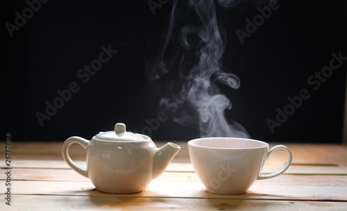 hot tea cup on wood table  Hot drink . with steam warm soft light  dark background.Good morning Tea or Have a happy day message concept.