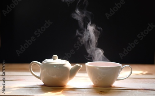 hot tea cup on wood table, Hot drink . with steam,warm soft light, dark background.Good morning Tea or Have a happy day message concept.