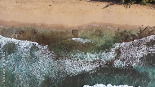 Waves breaking onto a sandy shoreline with colorful rock under the ocean, Gillin's Beach, Kauai photo