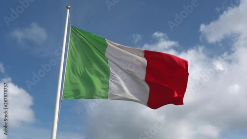 Waving almost straight Italian green, white and red flag in a strong wind with a royal blue sky and clouds in the background photo