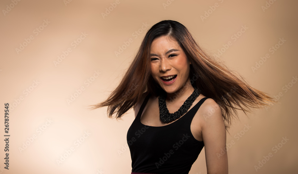 Fashion Young thin Asian Woman Tan skin brown hair beautiful make up fashion black vast dress posing throwing flying swing hair air. Studio Lighting beige yellow cream Background, summer beach hot sun Fashion Young thin Asian Woman Tan skin brown hair beautiful make up fashion black vast dress posing throwing flying swing hair air. Studio Lighting beige yellow cream Background, summer beach hot sun