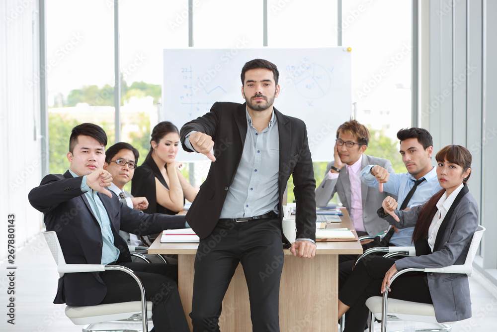 caucasian boss businessman showing thumb down or dislike with unhappy face with unsuccess multiethnic business team and business graph background caucasian boss businessman showing thumb down or dislike with unhappy face with unsuccess multiethnic business team and business graph background