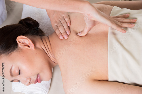 Body Massage on specific naked back of Asian woman by pressing fingers on pain or stress muscle point to release relax.  Therapist Spa body massage woman hands treatment on customer  isolated on white