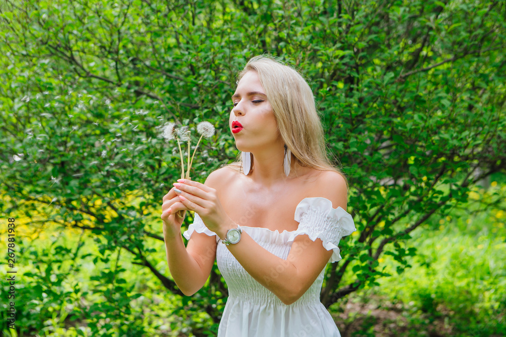 Beautiful blonde woman blowing on white blowball Beautiful blonde woman blowing on white blowball