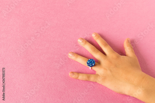 Funny ring on a little girl's hand. Isolated on pink background.