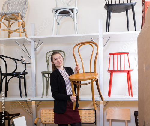 Woman seller suggesting wooden chairs photo