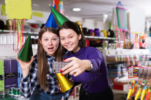 Comically dressed happy girls making funny selfies photo in shop