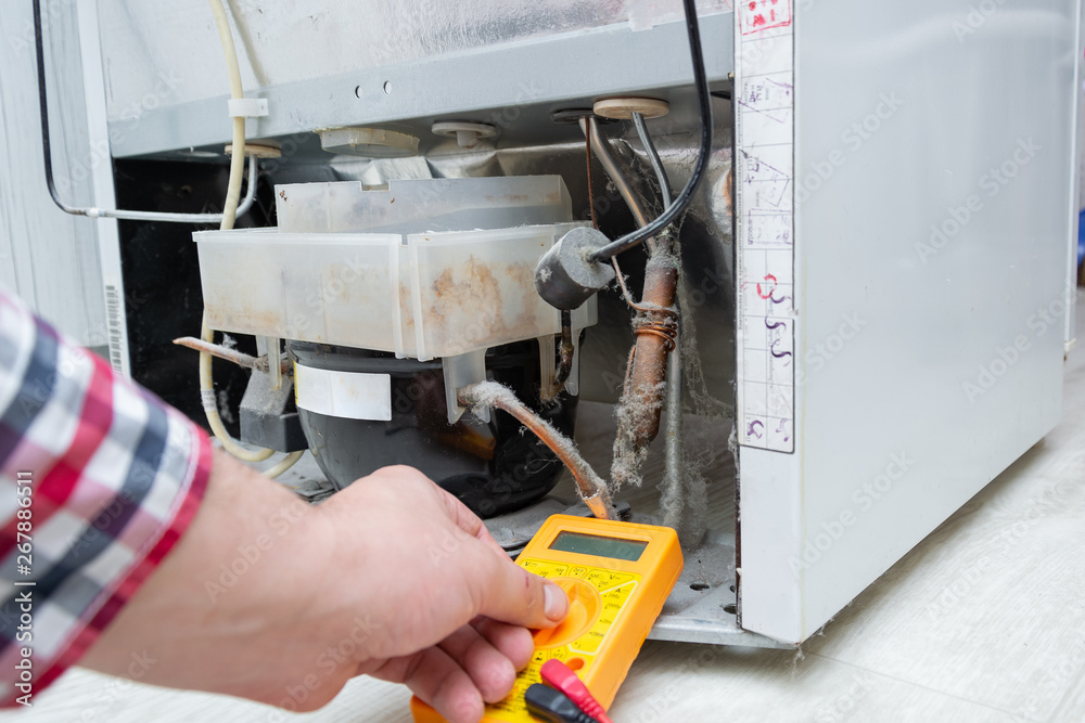 Male Technician Checking Fridge With Digital Multimeter. Repairman contractor repairing fridge and home appliances Male Technician Checking Fridge With Digital Multimeter. Repairman contractor repairing fridge and home appliances