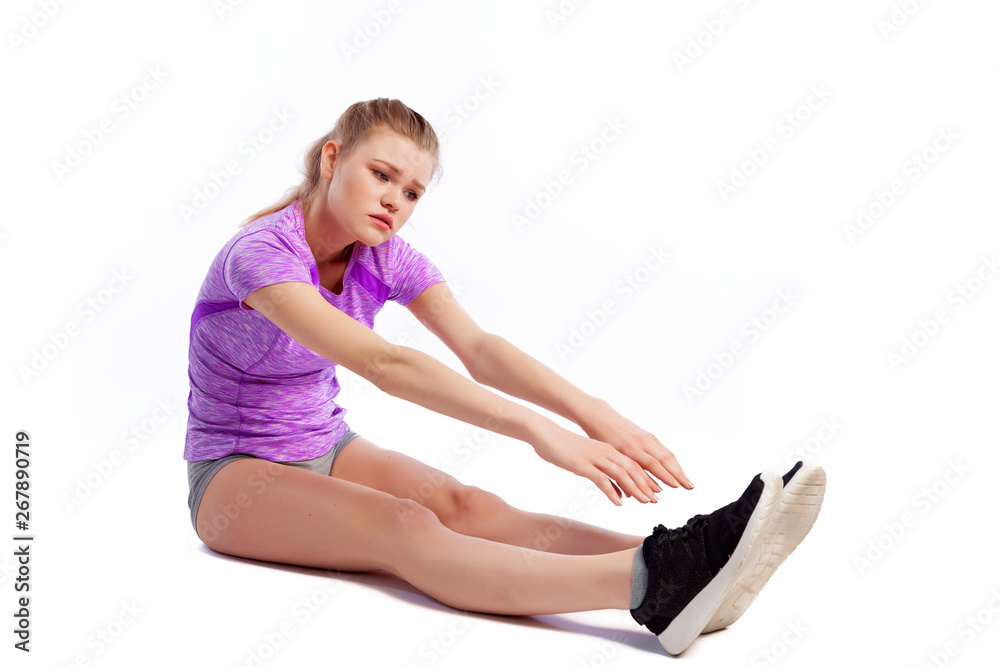 Young woman in sports clothes smilling, possing and stretching on the floor on white isolated background. Side view.Fit girl living an active lifestyle Young woman in sports clothes smilling, possing and stretching on the floor on white isolated background. Side view.Fit girl living an active lifestyle