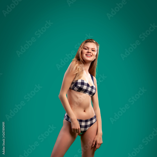 Beautiful woman with healthy body wearing in a black and white swimsuit and denim shorts  on green background.The concept of summer fashion swimsuit and relaxation © Виталий Сова