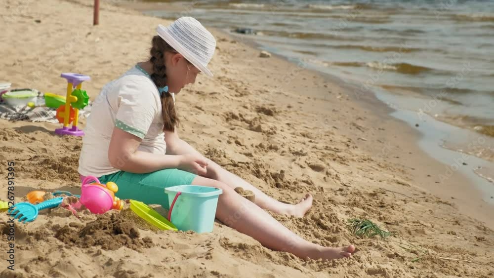 Girl builds a sand castle on the river bank Girl builds a sand castle on the river bank