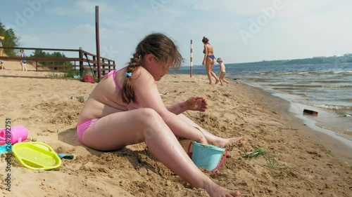  Girl builds a sand castle on the river bank