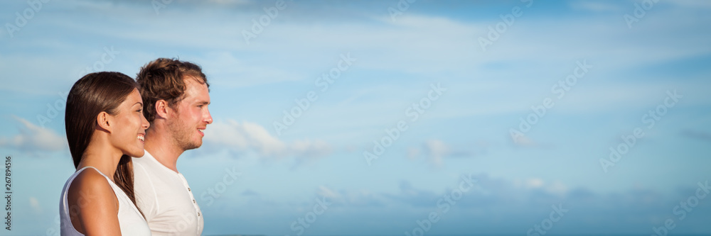 Happy young couple profile portrait banner. Two adults walking together smiling - interracial relationship Asian woman, Caucasian man. Copy space on blue background. Happy young couple profile portrait banner. Two adults walking together smiling - interracial relationship Asian woman, Caucasian man. Copy space on blue background.