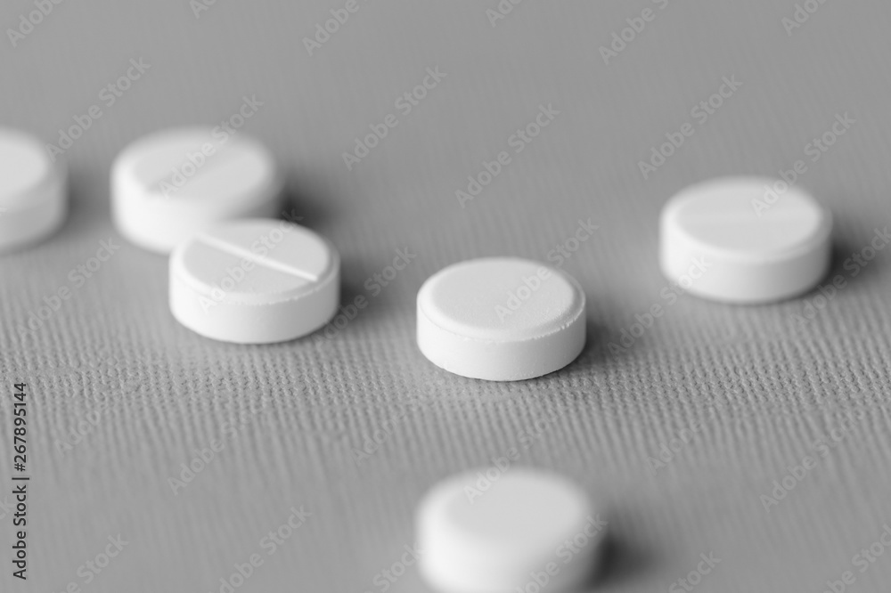 White tablets scattered on a gray surface close up. Black and white White tablets scattered on a gray surface close up. Black and white