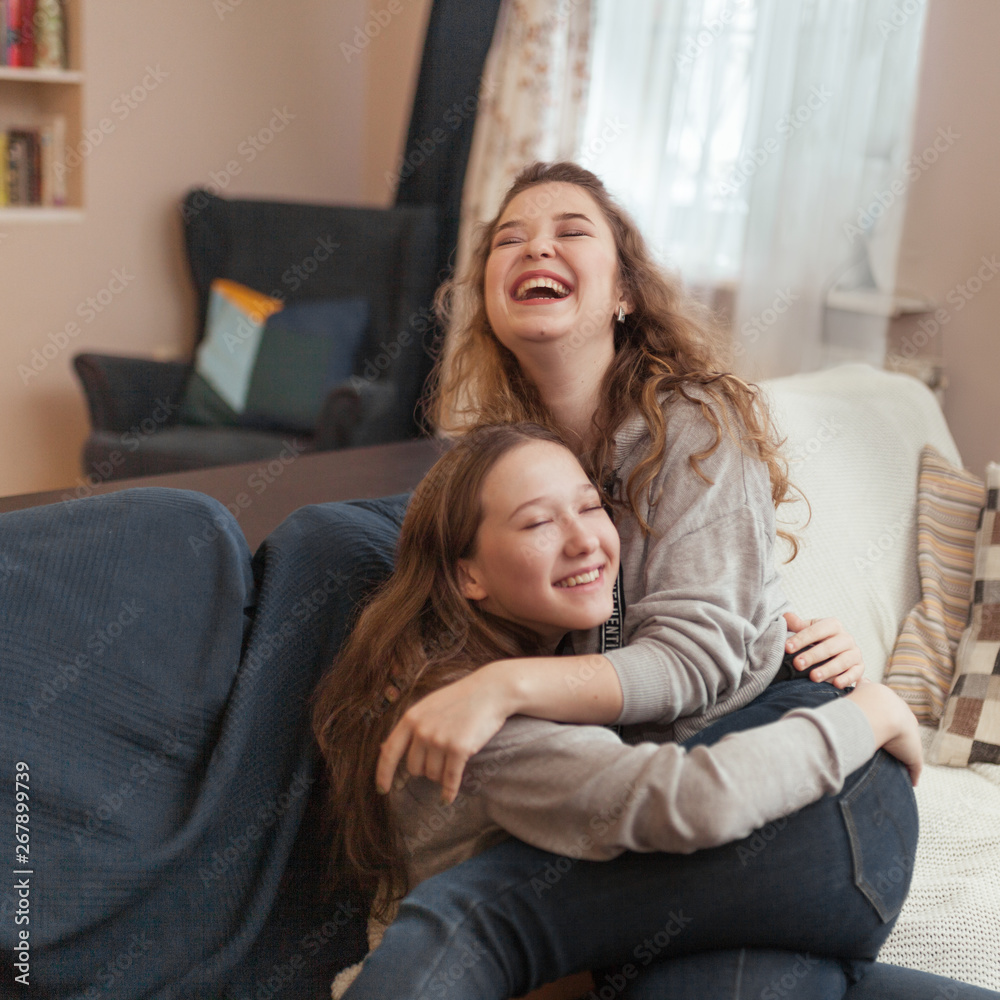 photo of two attractive happy woman friends hugging each other, indoor