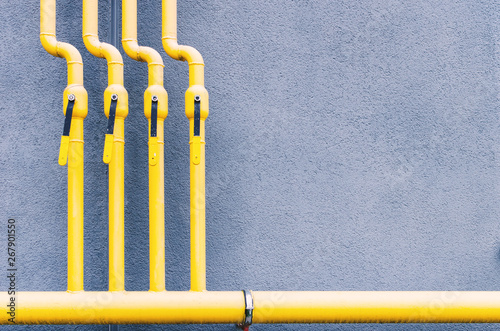 yellow gas pipe with a crane goes along the facade of a new multi-storey building.