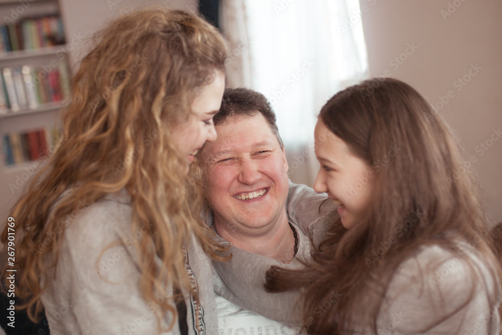 portrait of a happy father and beautiful daughters, they laugh, indoor